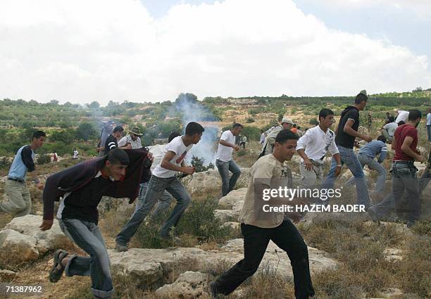 Palestinian youth run for cover after Israeli soldiers lobbed tear gas during a rally by Palestinians against the controversial separation barrier in...