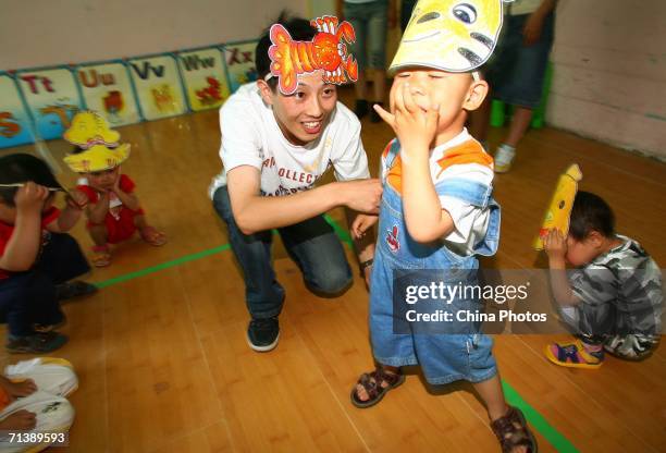 Huo Chengming, a teacher at the Golden Sun Bilingual Kindergarten, plays games with children on July 6, 2006 in Changchun of Jilin Province, China....