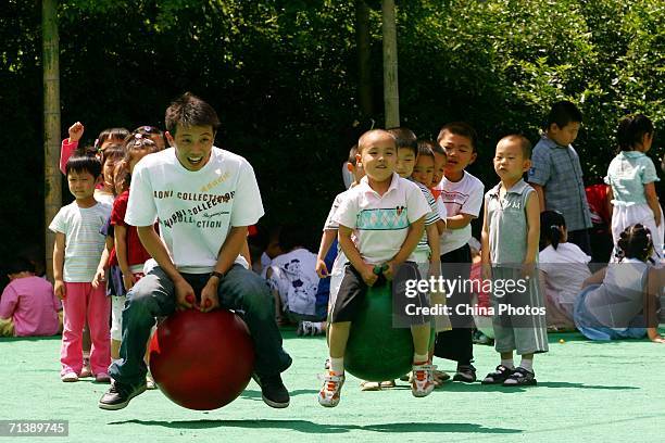 Huo Chengming, a teacher at the Golden Sun Bilingual Kindergarten, plays games with children on July 6, 2006 in Changchun of Jilin Province, China....