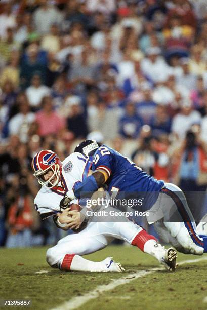 Linebacker Pepper Johnson of the New York Giants tackles quarterback Jim Kelly of the Buffalo Bills after a one yard gain in the fourth quarter of...