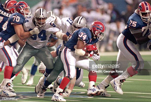 Running back Thurman Thomas of the Buffalo Bills battles for extra yards against the Dallas Cowboys defense during Super Bowl XXVIII at the Georgia...