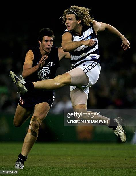 Cameron Mooney of the Cats kicks clear of Josh Kennedy of the Blues during the round 14 AFL match between the Carlton Blues and Geelong Cats at...