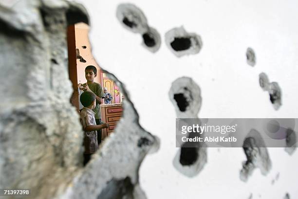 Palestinian boys survey their house damaged by by Israeli tank bullets on July 8, 2006 in Beit Lahia, northern Gaza Strip. According to reports...