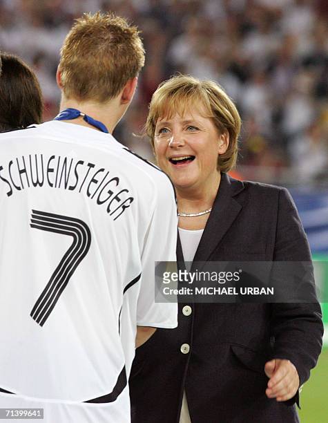 German Chancellor Angela Merkel congratulates German midfielder Bastian Schweinsteiger during a medal presentation ceremony following the team's...