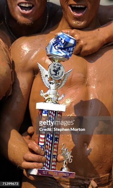Winner of the Redneck Mud Pit Belly Flop contest, Andrew Fremming of Oviedo, Florida, holds the trophy during the 11th annual games July 8, 2006 in...