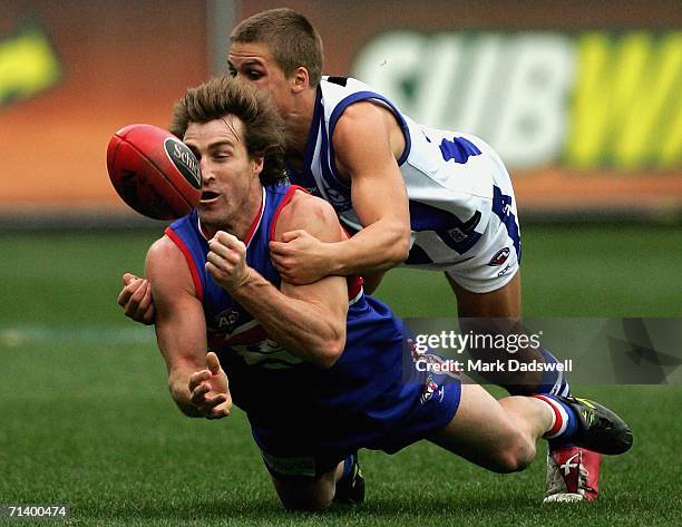 Scott West of the Bulldogs handballs clear of Andrew Swallow of the Kangaroos during the round fourteen AFL match between the Western Bulldogs and...