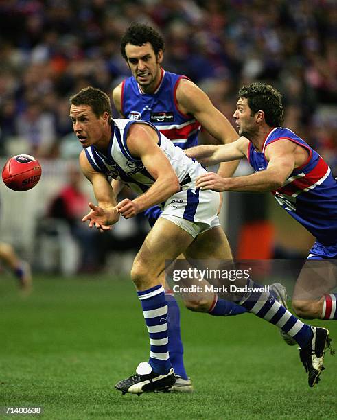 Kasey Green of the Kangaroos handballs clear of Rohan Smith of the Bulldogs during the round fourteen AFL match between the Western Bulldogs and the...