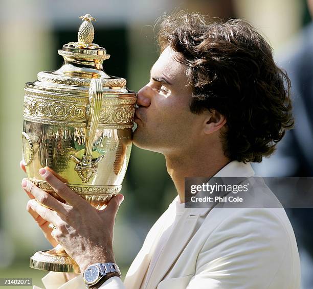 Roger Federer of Switzerland kisses the trophy after winning the Men's final against Rafael Nadal of Spain on day thirteen of the Wimbledon Lawn...