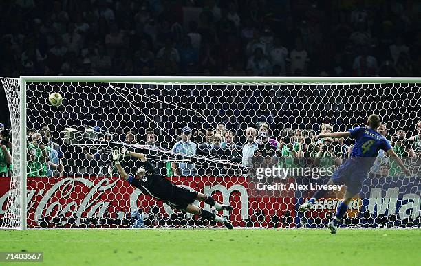 Daniele De Rossi of Italy scores a penalty kick past the dive of Fabien Barthez of France in a penalty shootout at the end the FIFA World Cup Germany...