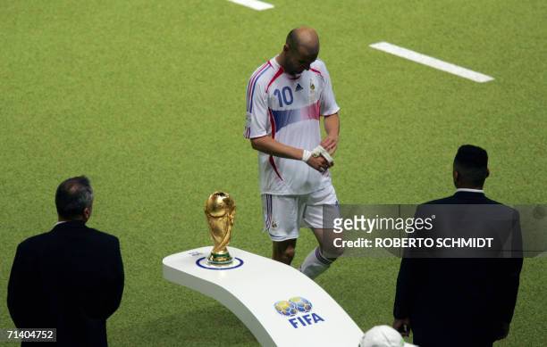 French midfielder Zinedine Zidane walks past the World Cup trophy being guarded by security as he leaves the pitch after getting a red card for...