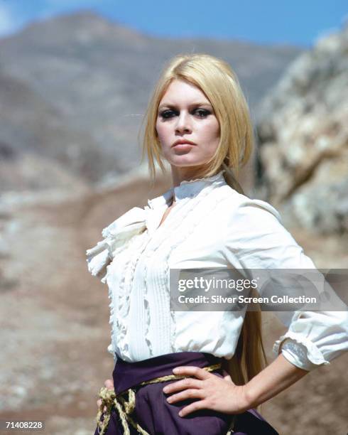 French actress Brigitte Bardot stands with her hands on her hips in a defiant pose during the filming of the western 'Shalako', circa 1968.