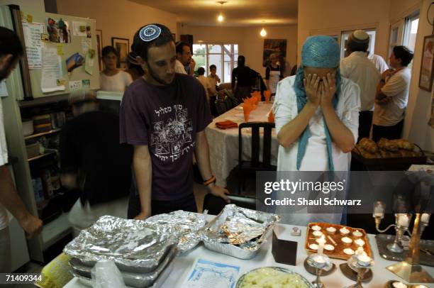 An Israeli settler covers her eyes in prayer as she lights traditional Jewish candles in honor of Shabbat at the house of the Golan family August 12,...