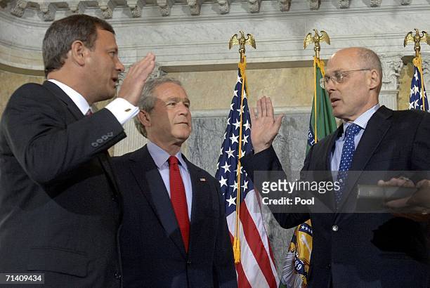 Investment banker Henry Paulson is sworn in by Chief Justice John Roberts as U.S. President George W. Bush looks on during a ceremony at the Treasury...