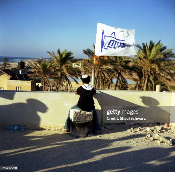 Young Jewish settler sits on the rooftop of an abandoned Palestinian house that has been taken over in the Muassi, the Palestinian area of the...