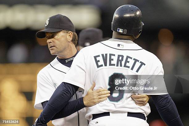 First base coach Mike Goff holds back Carl Everett of the Seattle Mariners as he argues with second base umpire Chuck Meriwether during the game...