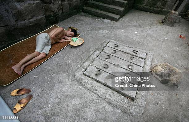 Man and a dog sleep by the entrance to one of sixteen funk holes that have been opened by the Chongqing government, as a refuge from the heat wave on...