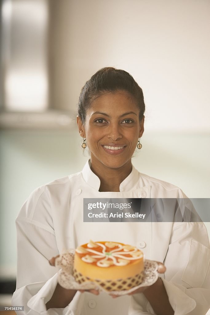 African female pastry chef holding a cake