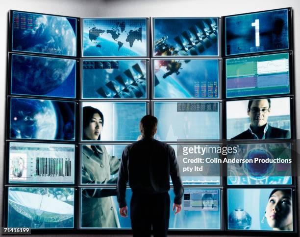 businessman standing in front of television screens displaying technology - multiple screens stock pictures, royalty-free photos & images