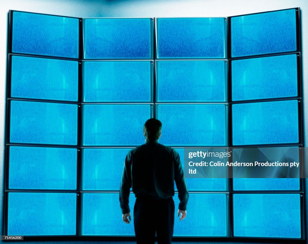 Businessman standing in front of blank television screens