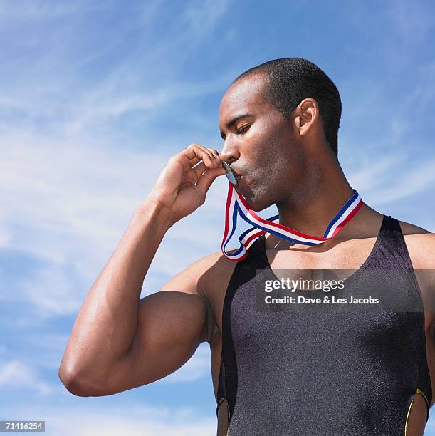 african male athlete kissing medal - médaillé photos et images de collection