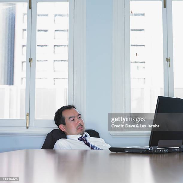 asian businessman slouched down in his chair - verkeerde houding stockfoto's en -beelden