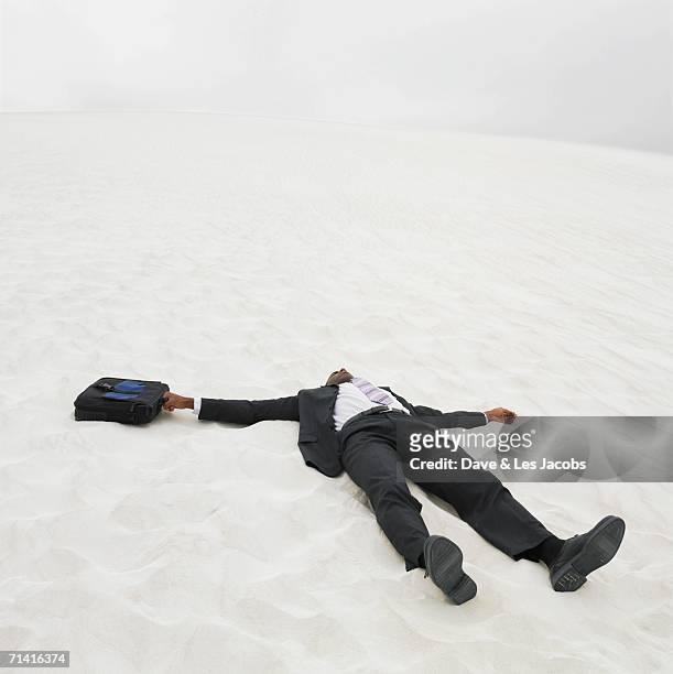 african businessman lying in the sand - dead body stockfoto's en -beelden