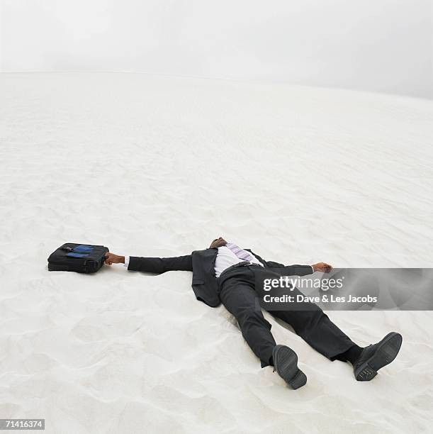 african businessman lying in the sand - cadáver - fotografias e filmes do acervo