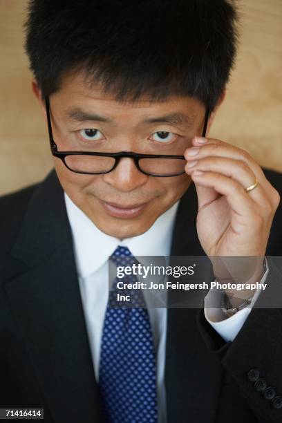 senior asian businessman pulling down his eyeglasses - taking off glasses stock pictures, royalty-free photos & images