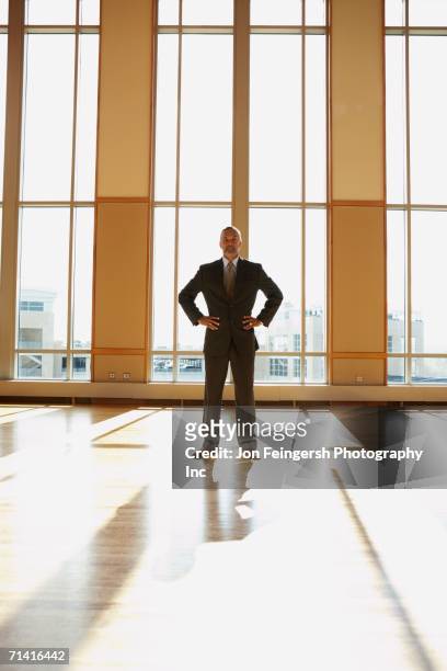 businessman standing in sunlit room with hands on his hips - bethesda maryland fotografías e imágenes de stock