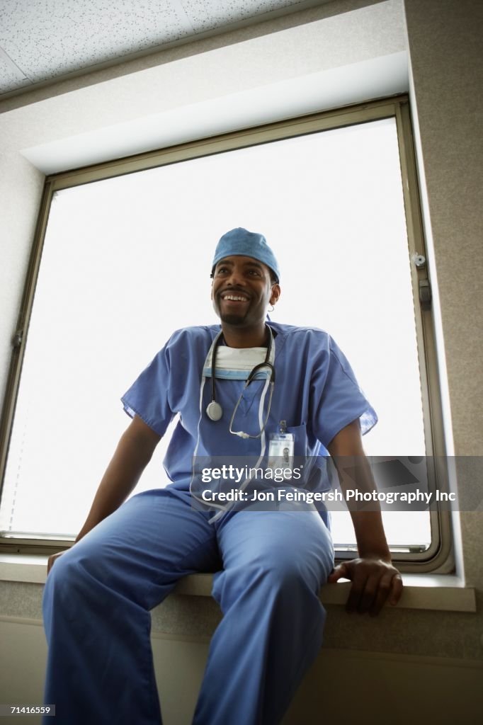 African male surgeon sitting in window alcove