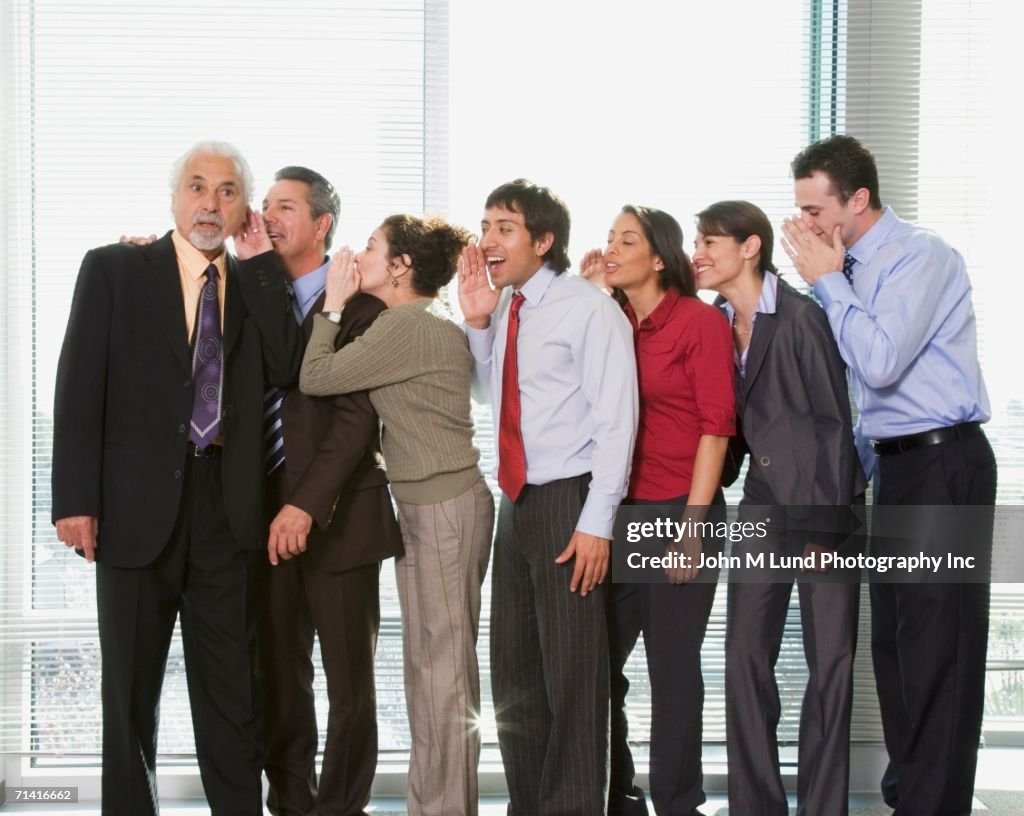 Group of businesspeople whispering in each other's ears