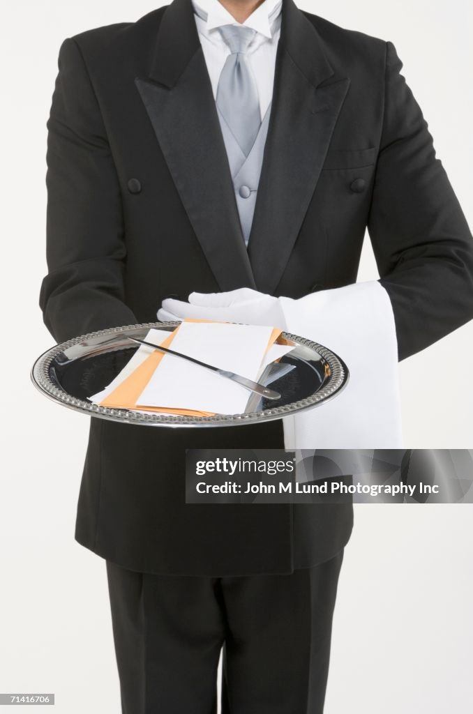 Butler holding a silver tray with mail and a letter opener