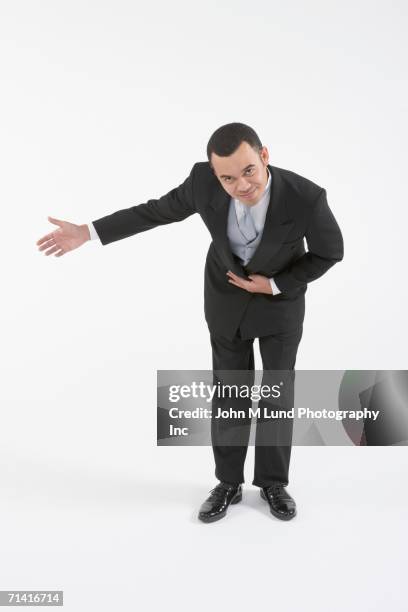 asian butler bowing and making a welcoming gesture - 曲げる ストックフォトと画像