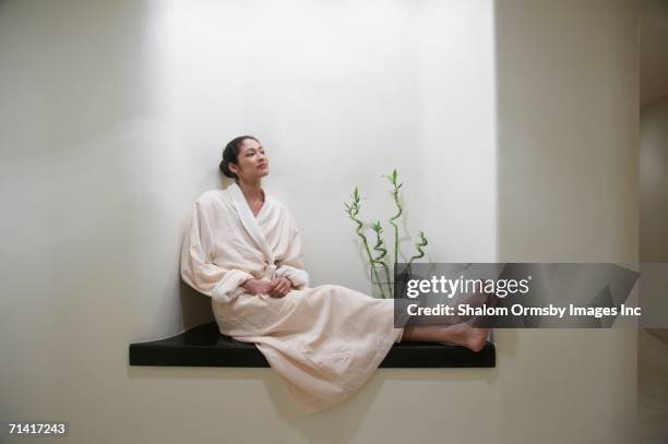 woman in bathrobe sitting in spa alcove - bathrobe fotografías e imágenes de stock