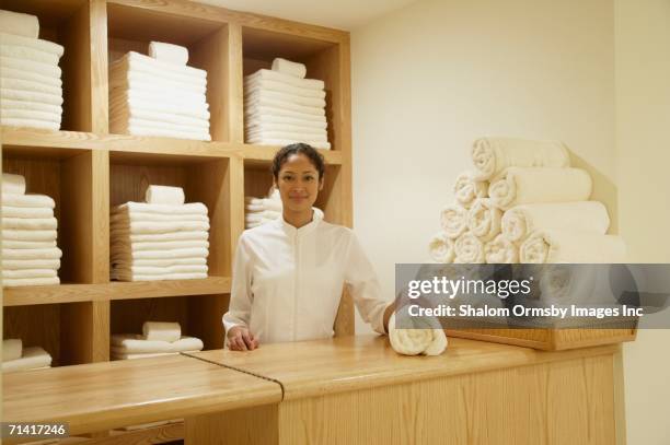 spa employee behind counter with rolled towels - hotel uniform stock-fotos und bilder