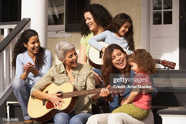 female hispanic family members sitting on the porch playing guitar - sister act stock pictures, royalty-free photos & images