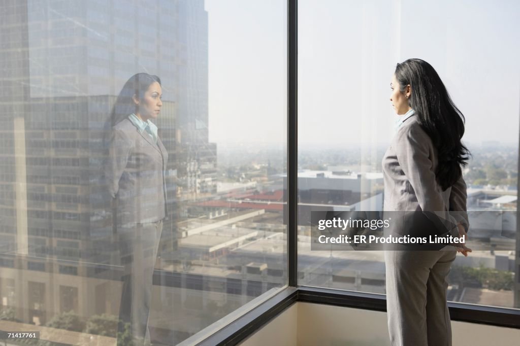 Hispanic businesswoman looking out a window