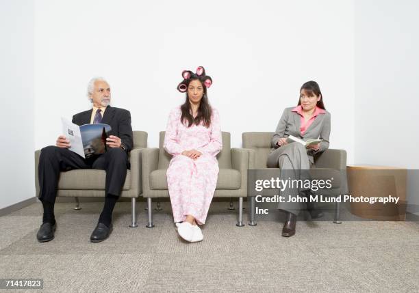 hispanic woman in pajamas and curlers sitting next to business people - hair curlers stock pictures, royalty-free photos & images