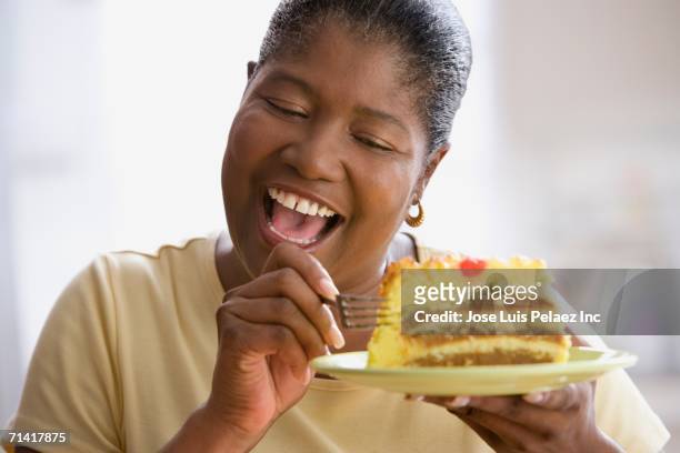 middle-aged african woman about to eat a piece of cake - eating cake stock pictures, royalty-free photos & images