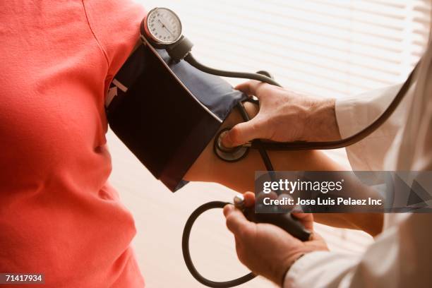 overweight woman having her blood pressure checked - bloeddrukmeter stockfoto's en -beelden