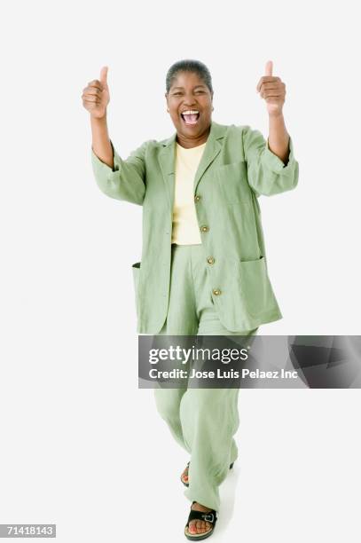 studio shot of senior african woman smiling and giving the thumbs up - pouce levé fond blanc photos et images de collection