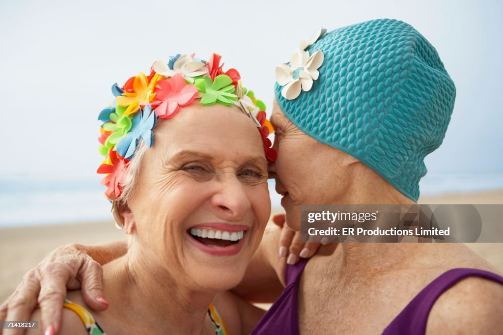 Two senior women in swim caps at the beach