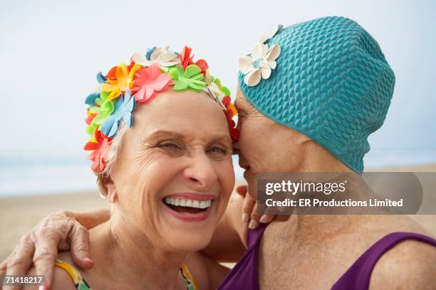 two senior women in swim caps at the beach - chuchoter photos et images de collection