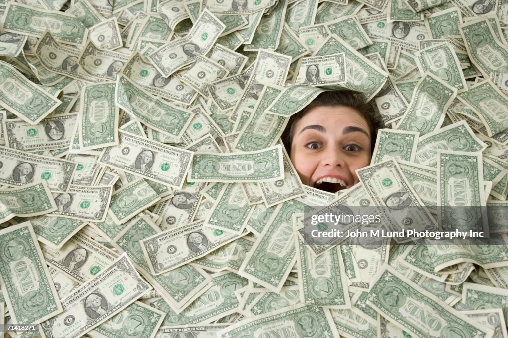 Woman's face peeking out of a pile of money