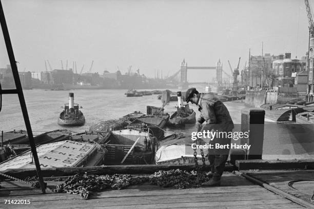 Barges and tugboats on the stretch of the River Thames known as the Pool of London, with Tower Bridge in the background, 3rd December 1949. Original...