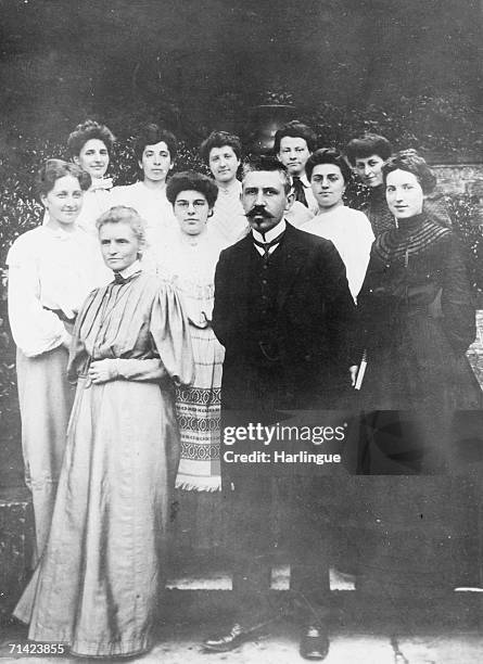 French physicists Paul Langevin and Marie Curie stand in front of a group of women on steps, Paris, early 1910s.