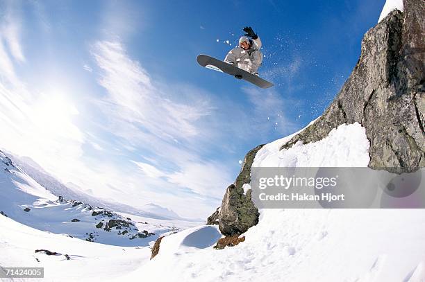 a snowboarder jumping out from a cliff. - snowboard jump bildbanksfoton och bilder