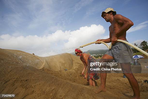 Sand artists Marjon Katerberg of Holland, and Pedro Mira of Portugal, add finishing touches to a sand sculpture on the Nansha Beach on July 12, 2006...