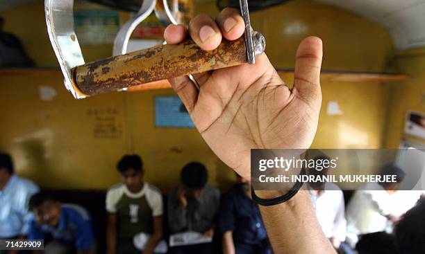 Commuter with a sacred thread to ward off evil spirits wound onto his wrist travels in a city bound local train in Mumbai, 13 July 2006. The death...