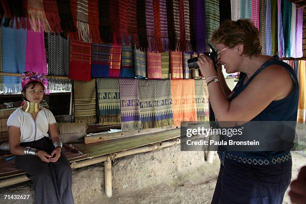 Foreign tourist takes a photo of Mah Su a Long Neck Padaung hill tribe girl at a handicrafts stall in a small village where 30 familes live July 13,...